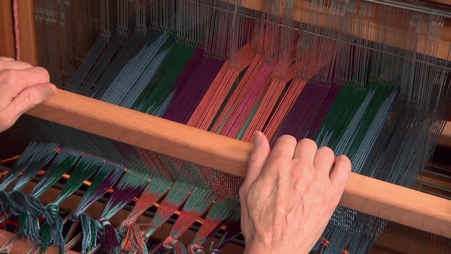The second pick goes through the alternate plain weave shed, but it is not beaten into place. In this image, Rosalie is leaning the beater forward so she can open the next shed and strum behind the reed.