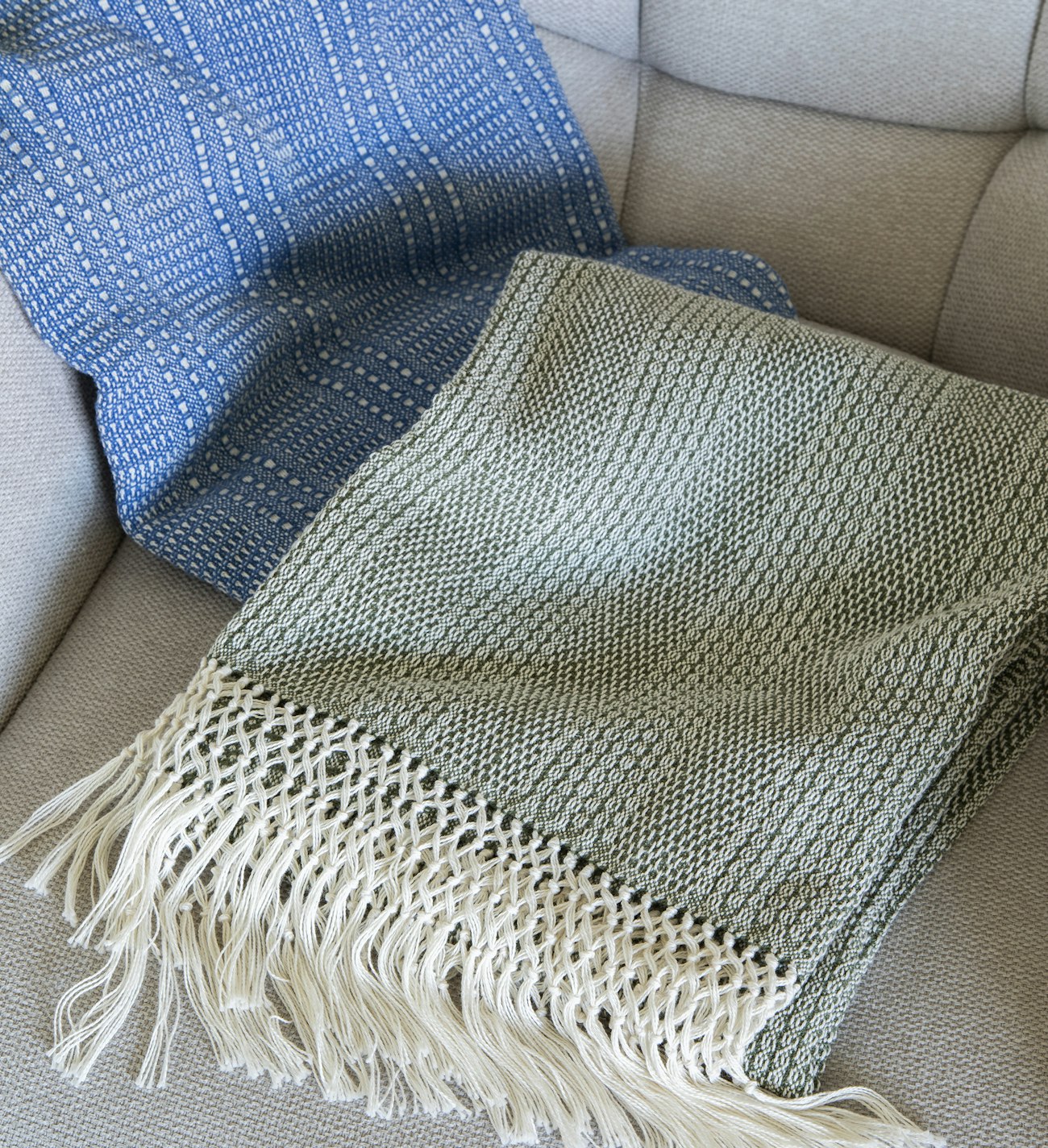 Blue and green throws on an upholstered chair.