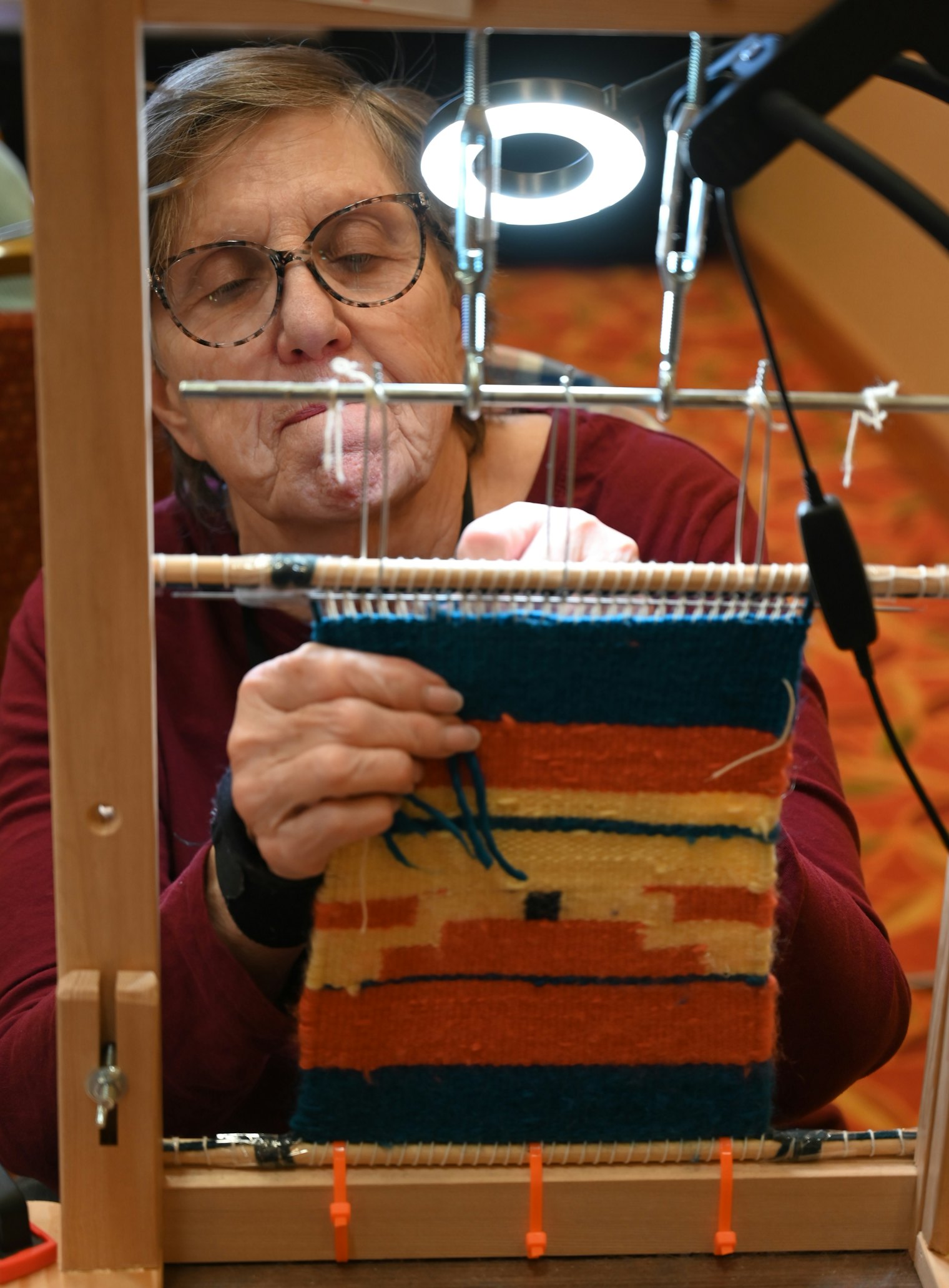 A weaver carefully finishes her Diné tapestry at Weave Together 2026.