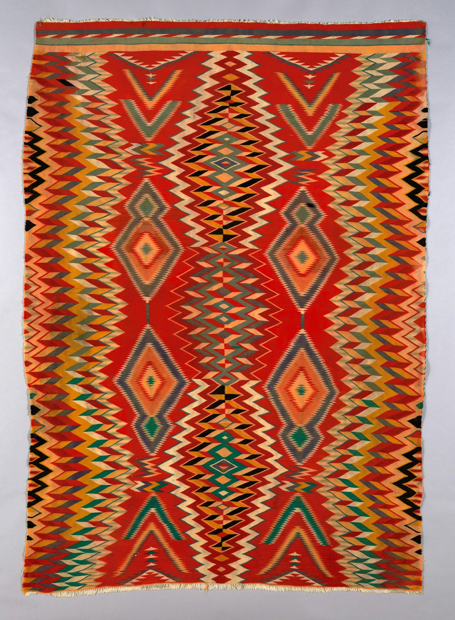 Germantown Eye-Dazzler rug. The Navajo/Diné creator of this blanket used the intense color of commercially dyed yarns and the Saltillo weaving style. Interlocking serrated undulating lines appear to vibrate over the entire surface. Source: Arizona, New Mexico, and Utah. 1800/90. Courtesy of Art Institute of Chicago, CC0 license