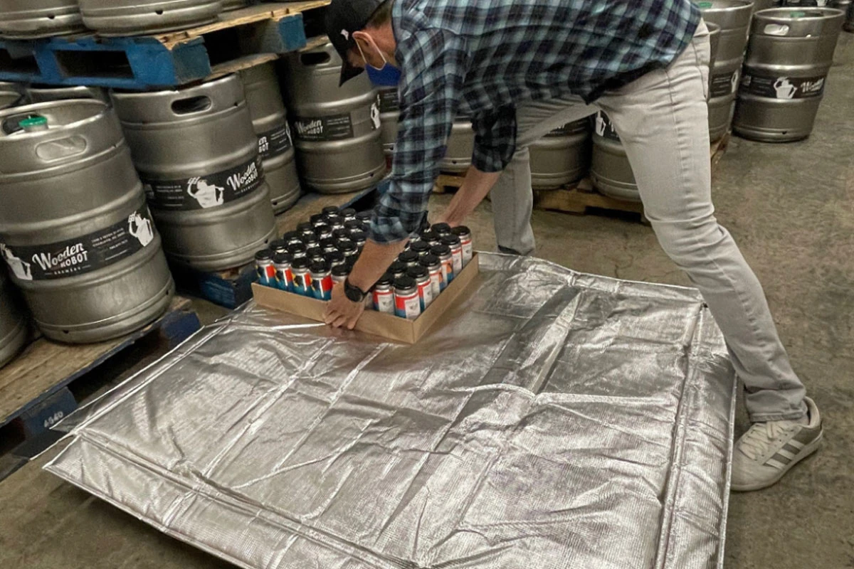 A brewery owner carefully stacks beer onto a pallet equipped with the Pallet Parka.