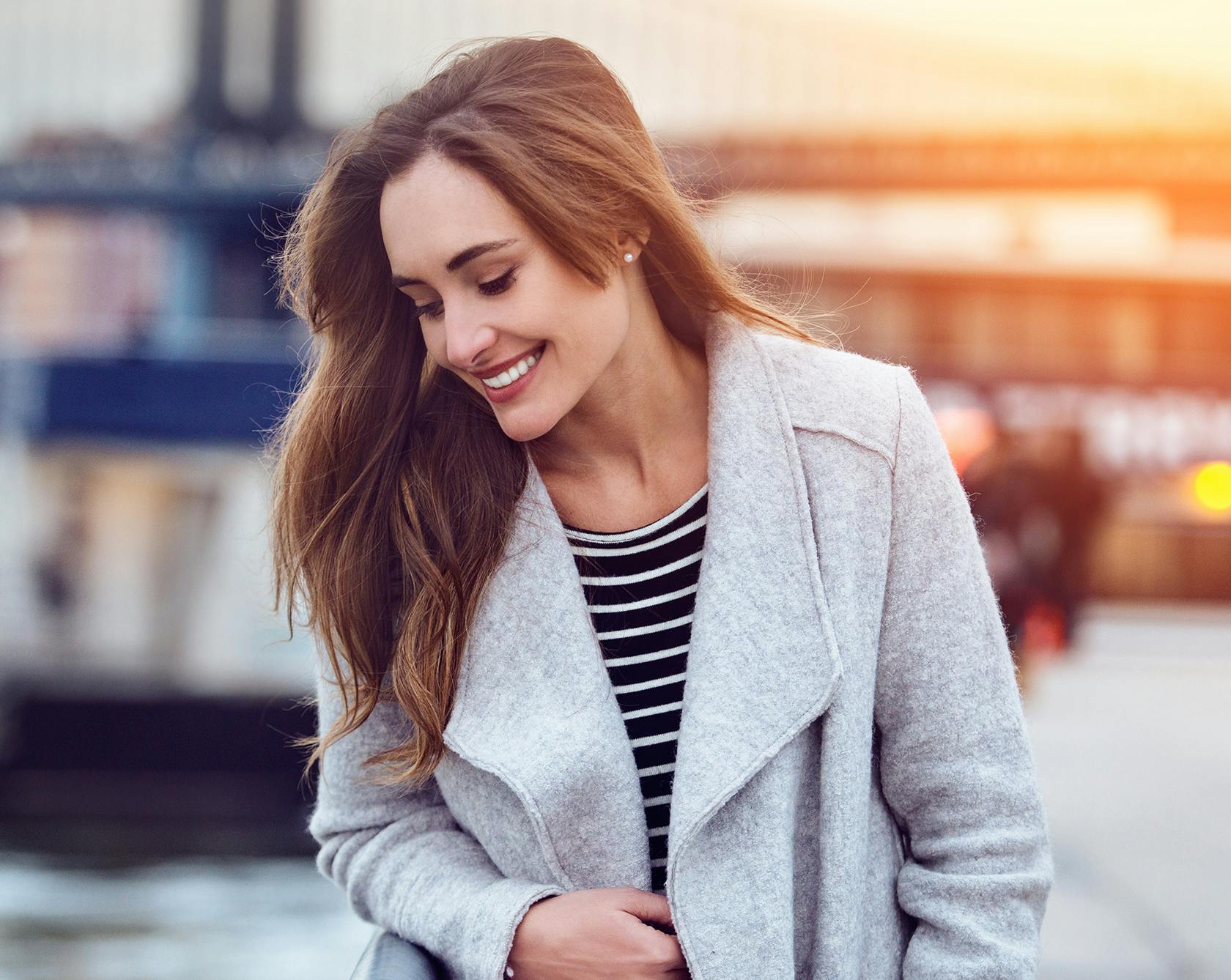 beauitful young woman smiling wearing a light gray jacket