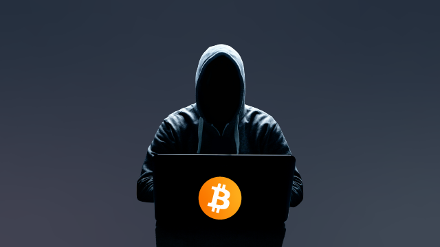 A dark figure stands behind a podium with the Bitcoin logo on it.