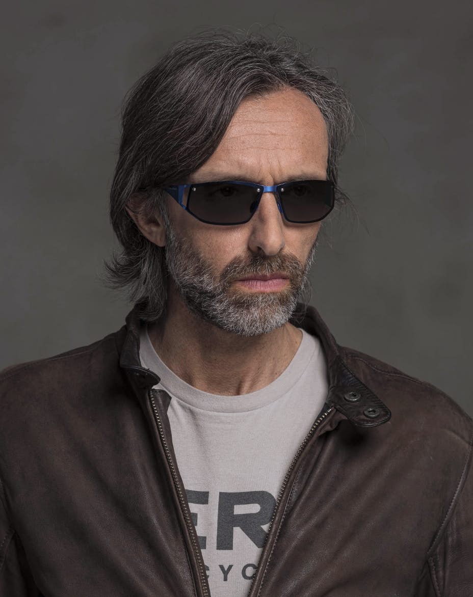 The model is wearing Cosmic Dark Blue glasses with smoke lenses