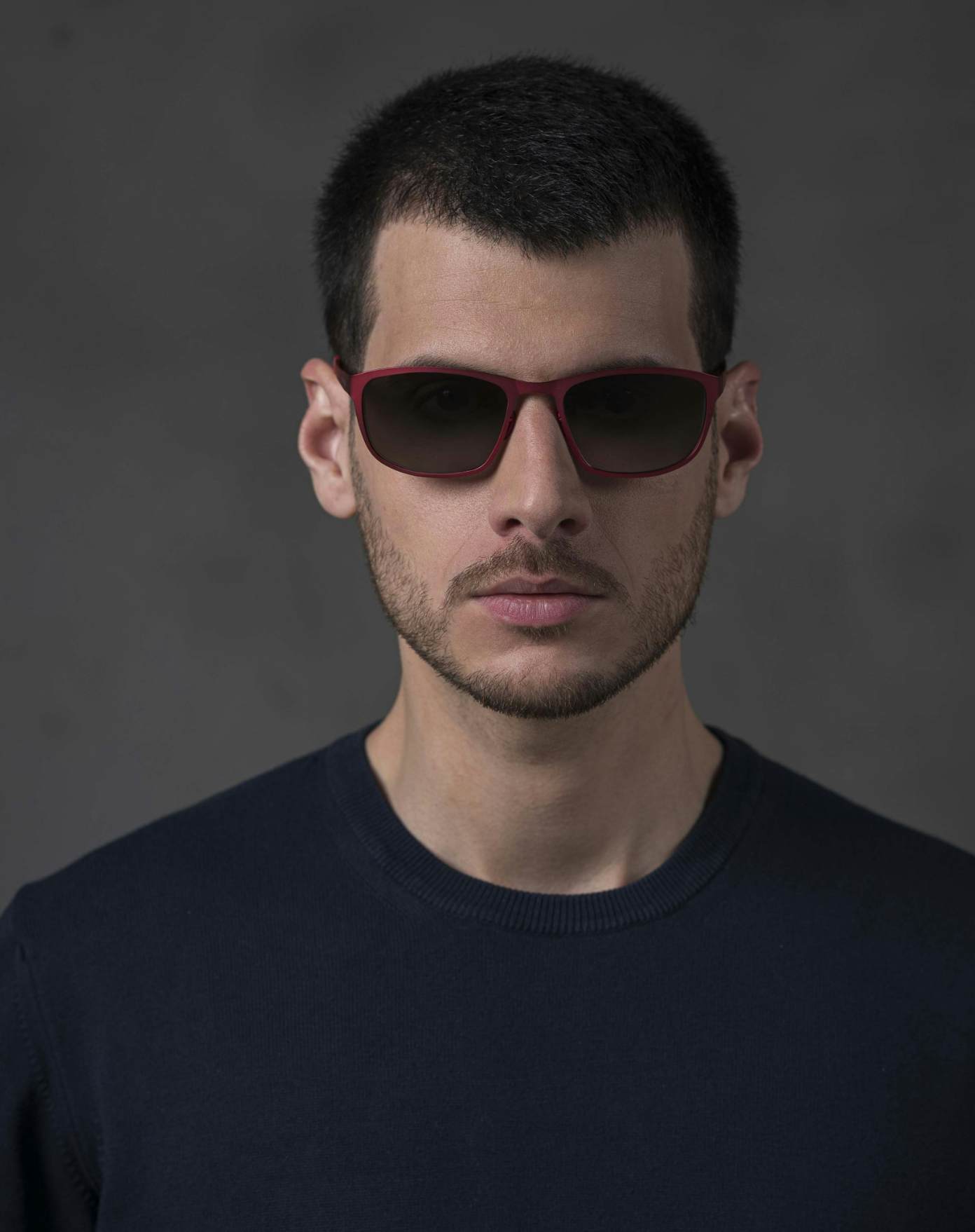 The model is wearing Atom Red glasses with smoke lenses