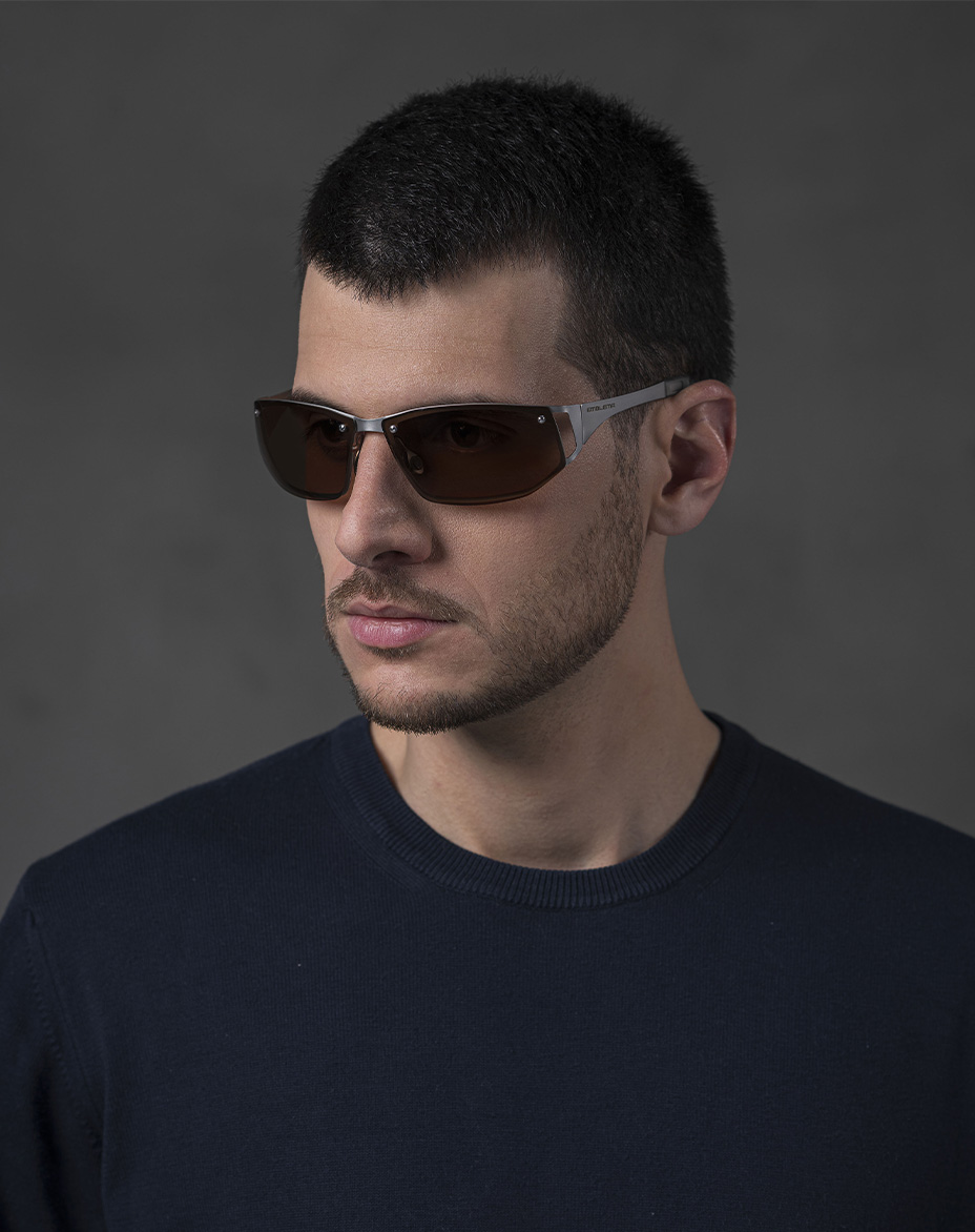The model is wearing Cosmic Palladium glasses with brown lenses