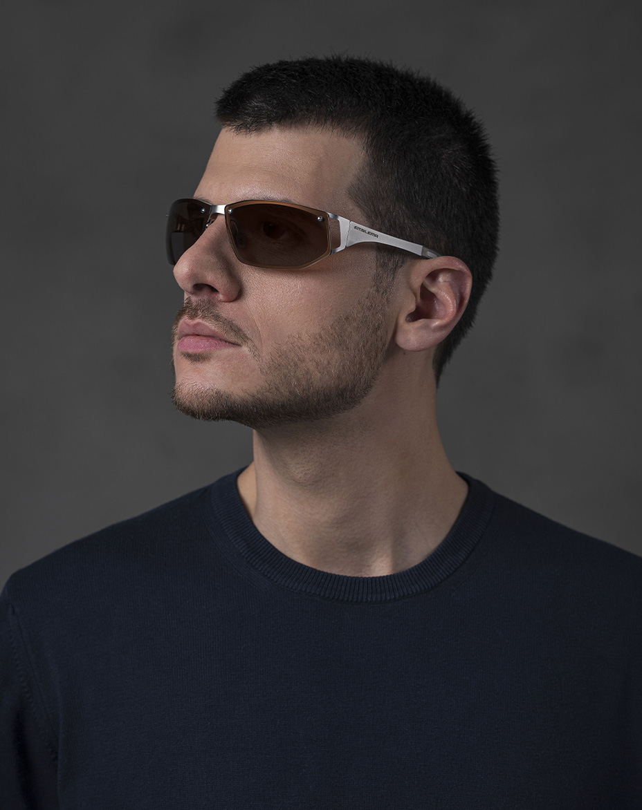 The model is wearing Cosmic Palladium glasses with brown lenses