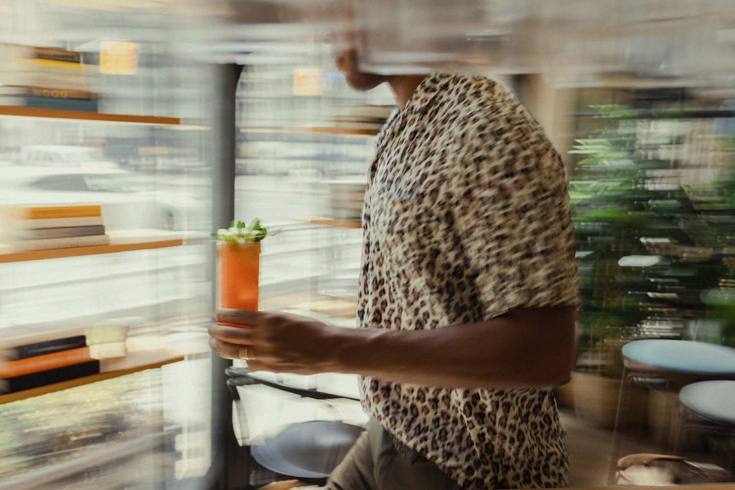 Server carrying a vibrant summer cocktail through the interior of Walrus Pub & Beer Hall in Toronto