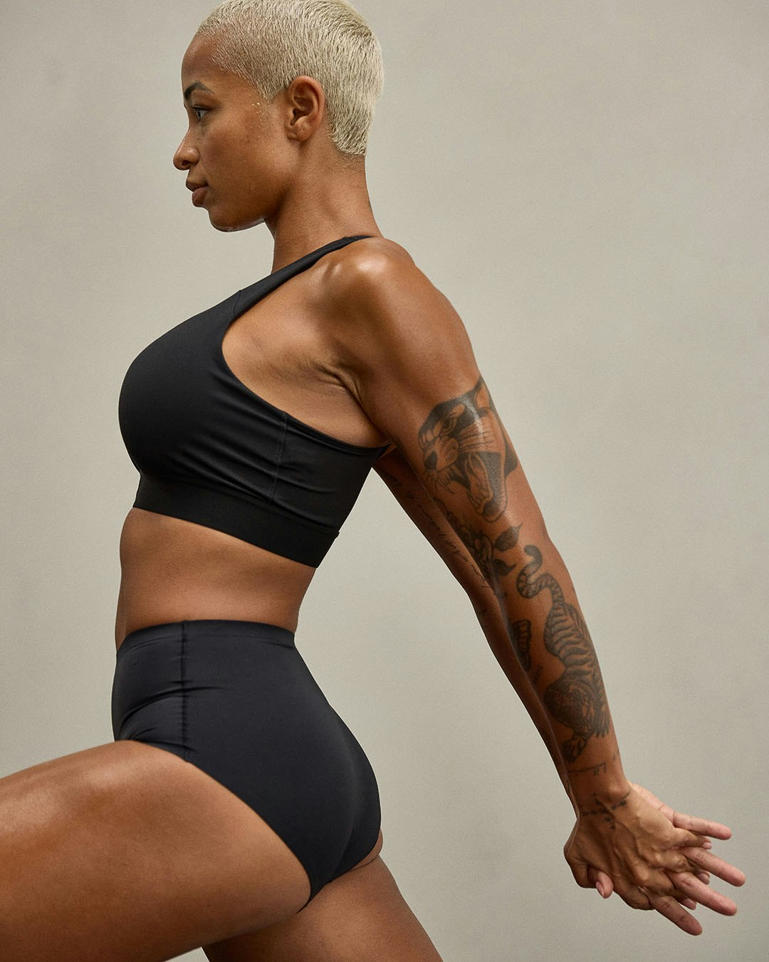 En person i menstrosor och sport-bh utför en stretchövning.