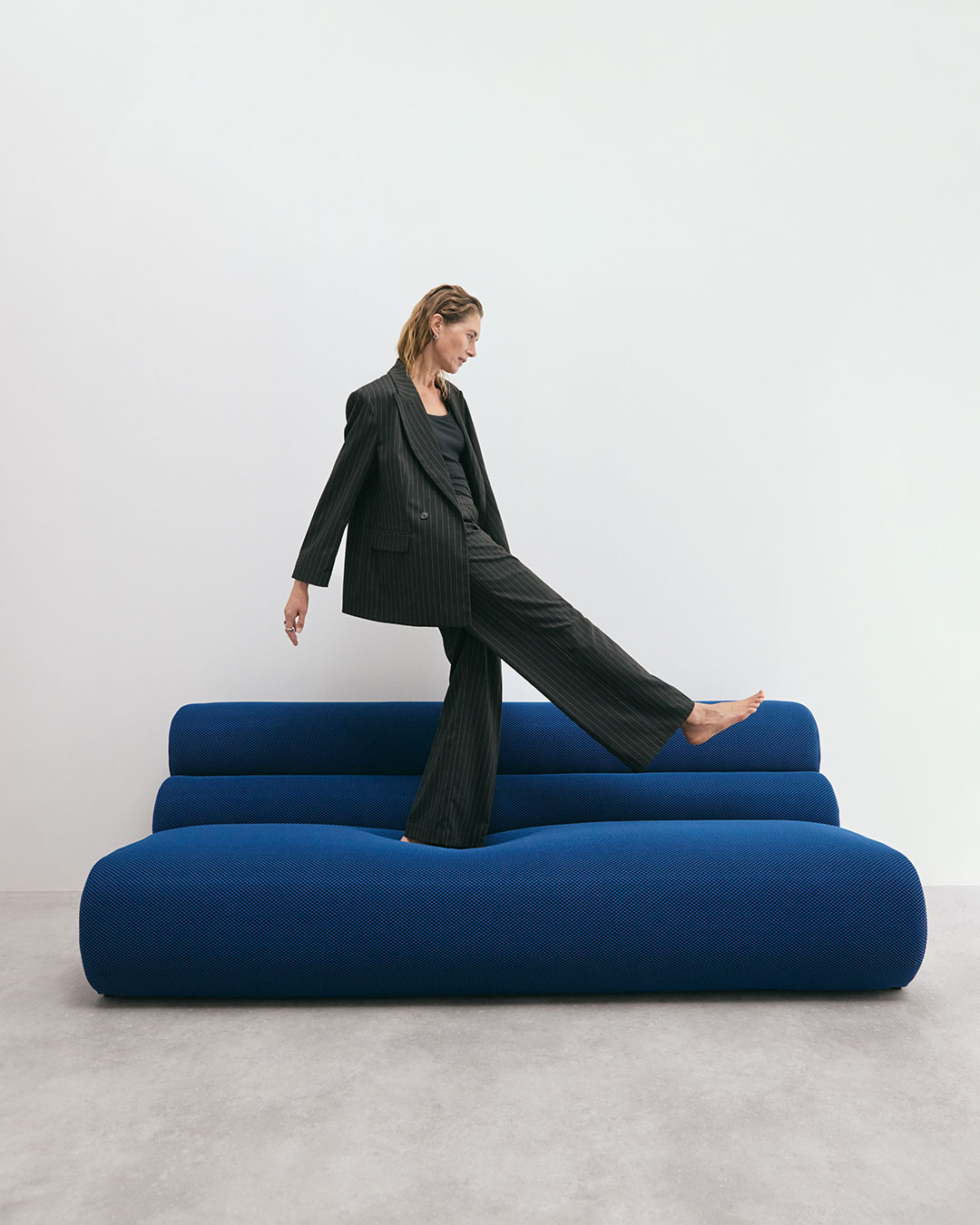 Nainen seisoo sinisellä sohvalla