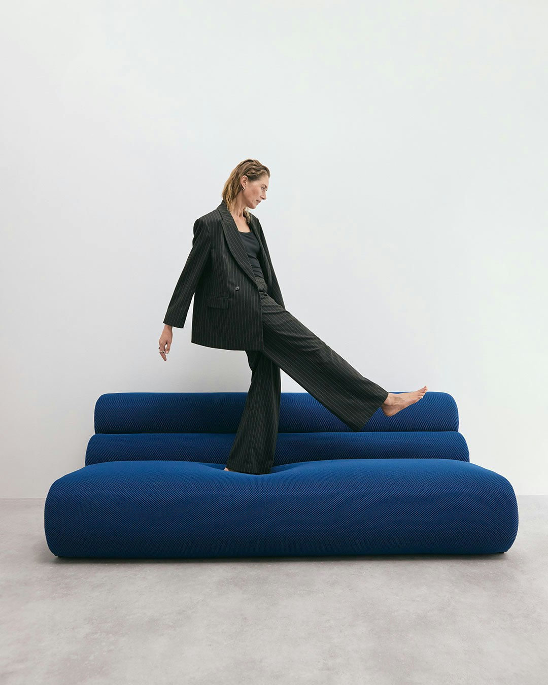 Nainen seisoo sinisellä sohvalla