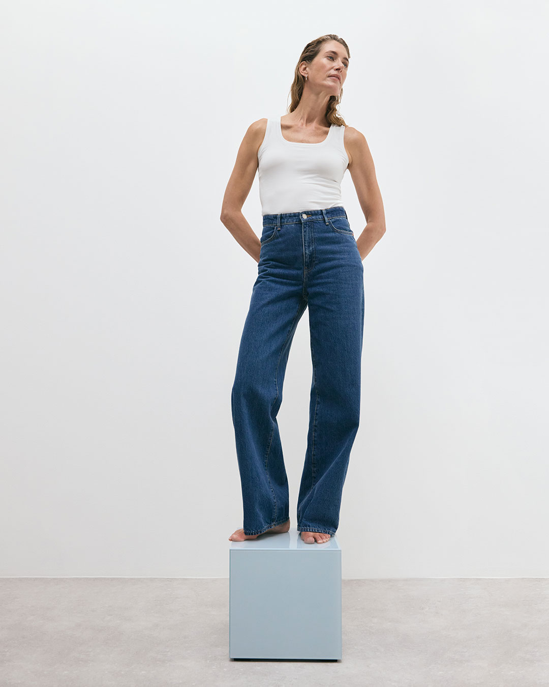 Nainen valkoisessa vaihdevuosi-topissa ja farkuissa