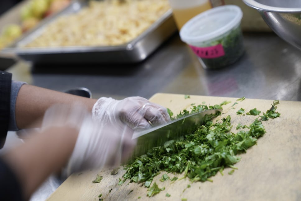 A crew member at The Door's onsite kitchen, chopping herbs for our weekday dinner service.
