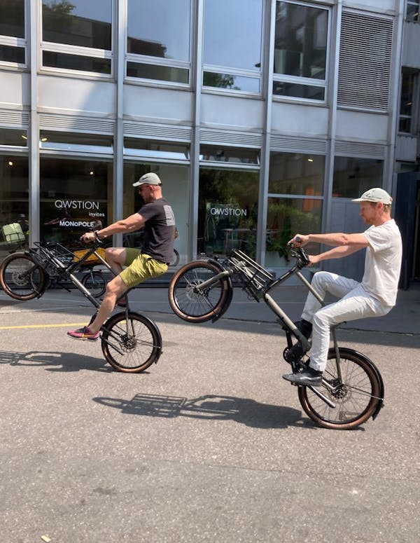 two men doing wheelie on cargo bikes