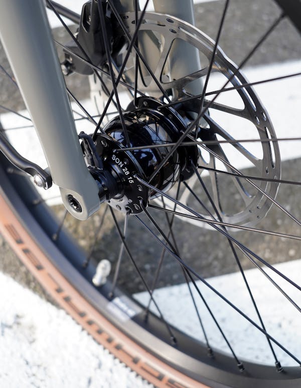 Close-up of bike wheel, break and light dynamo.