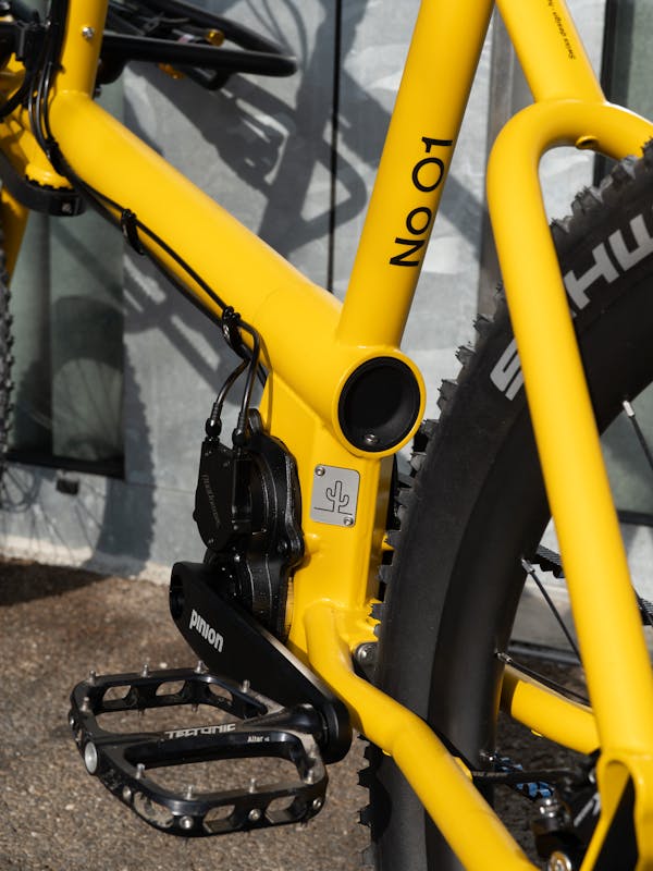 Close-up of the Pinion drivetrain, OneUp Aluminum Pedals, and custom Desertus Bikus plate.