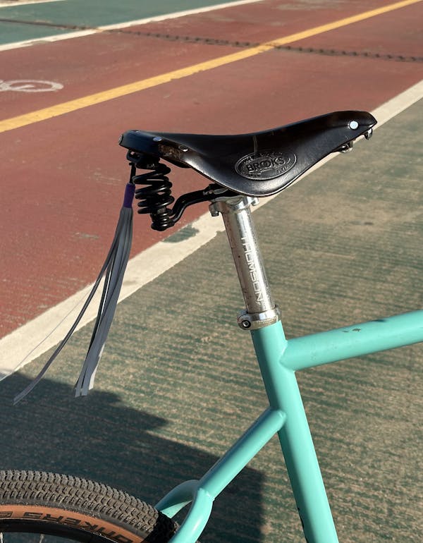 Close-up of a custom blue MONoPOLE cargo e-bike, featuring a Brooks saddle, and a Thomson seat post.