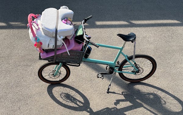 Top view of custom blue MONoPOLE cargo e-bike, featuring the front Platform rack, grey crate, and belt drive steering, parked on a bike lane.