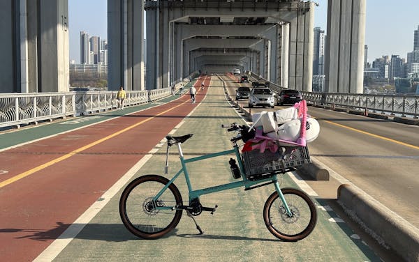 Custom blue MONoPOLE cargo e-bike, featuring the front Platform rack, grey crate, and belt drive steering, parked on a bike lane.
