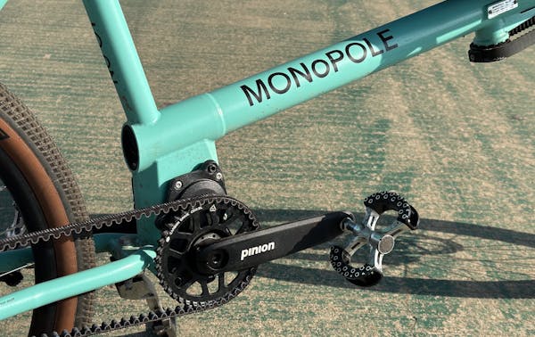Close-up of a MONoPOLE blue cargo e-bike with a Pinion gearbox, parked on a bike lane.