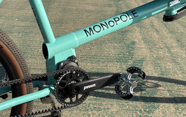 Close-up of a MONoPOLE blue cargo e-bike with a Pinion gearbox, parked on a bike lane.