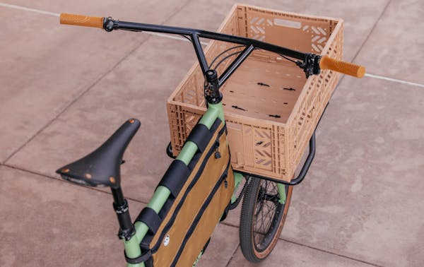 Compact MONoPOLE custom cargo bike with a Stridsland Bullship Stem, and front-loading rack with dust pink crate.