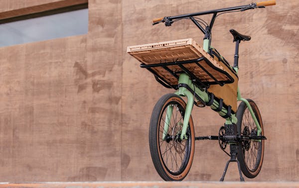 MONoPOLE green mini cargo bike featuring a milk tea pink crate on the front.