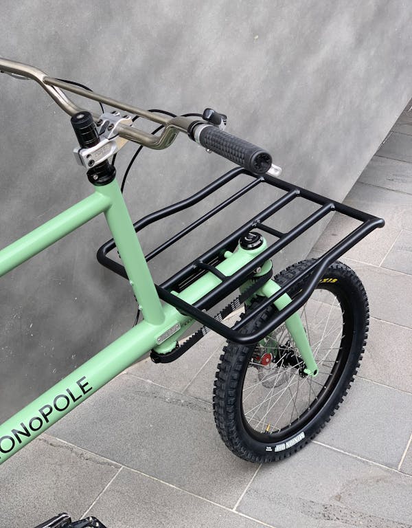Detail shot from behind of a custom green MONoPOLE cargo bike with platform rack and BMX-inspired design
