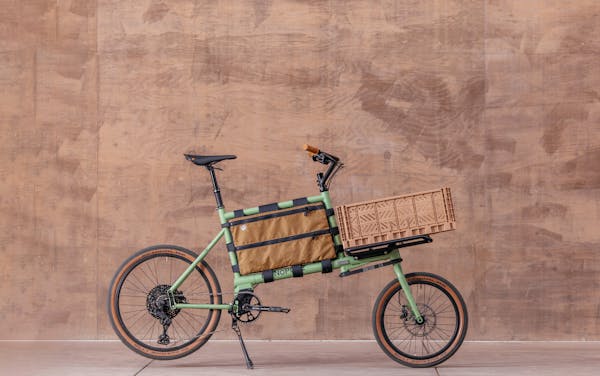 MONoPOLE green mini cargo bike featuring a milk tea pink crate on the front.