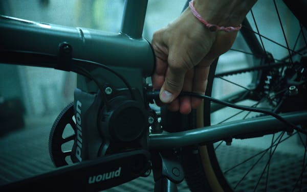 Detail shot of a hand connecting the charging cable to a MONoPOLE cargo e-bike with Pinion gearbox