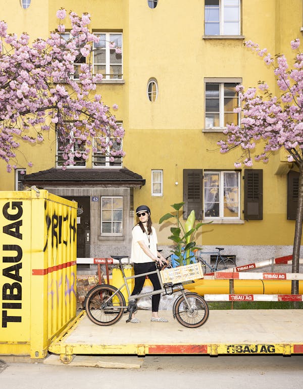 Woman carrying plants on a cargo bike with yellow crate