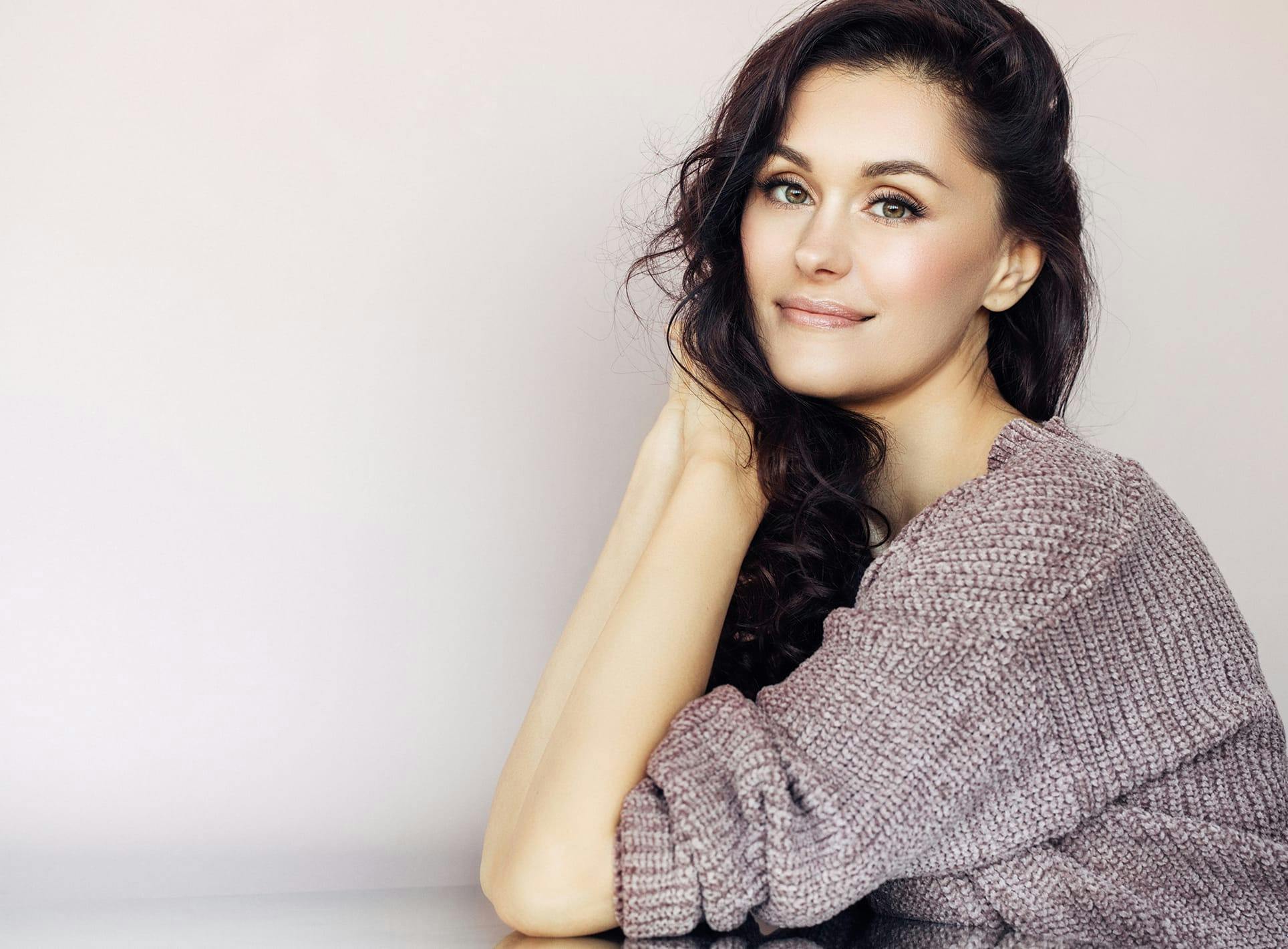 A woman in a gray sweater with beautiful cheeks.