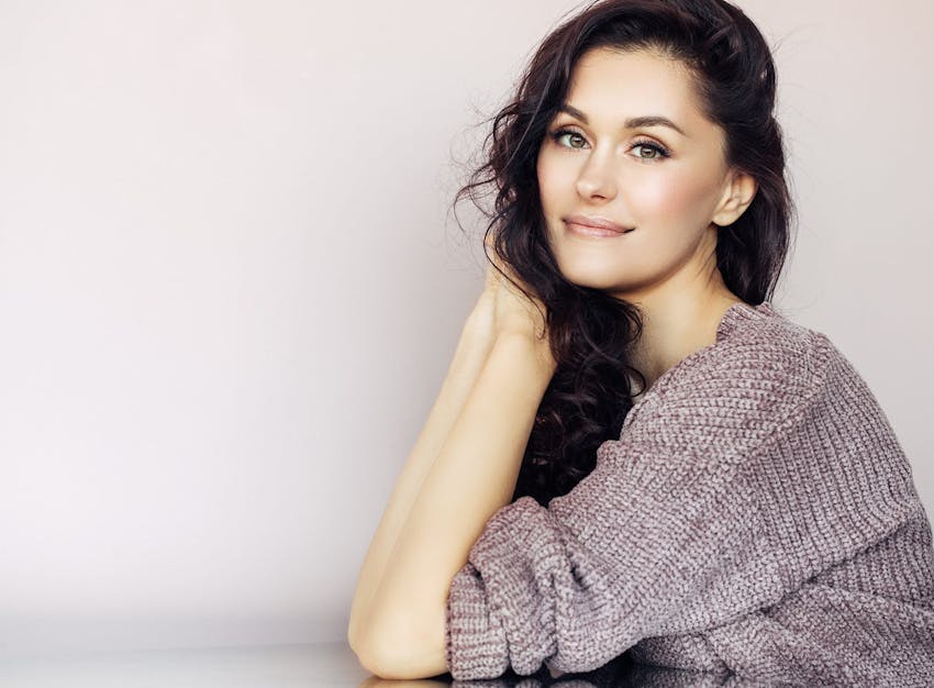 A woman in a gray sweater with beautiful cheeks.