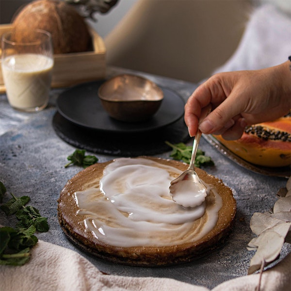 Mão recheando torta de mamão com colher de prata