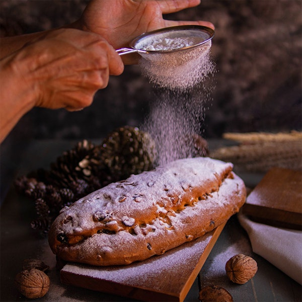 Mão jogando açúcar sob Stollen de natal