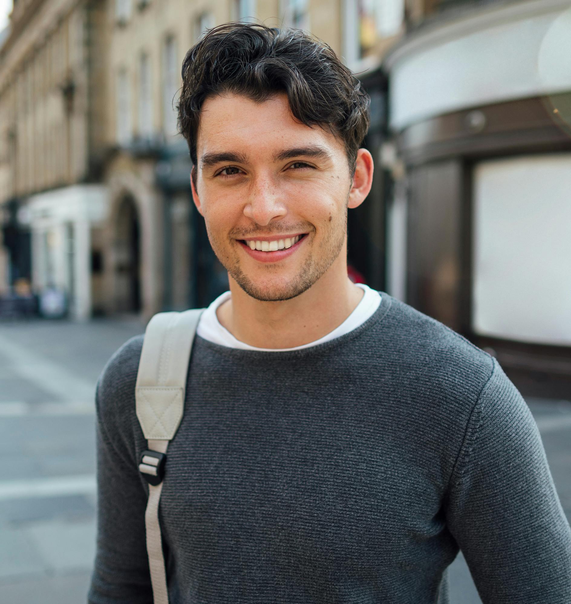 Man smiling with one backpack strap on