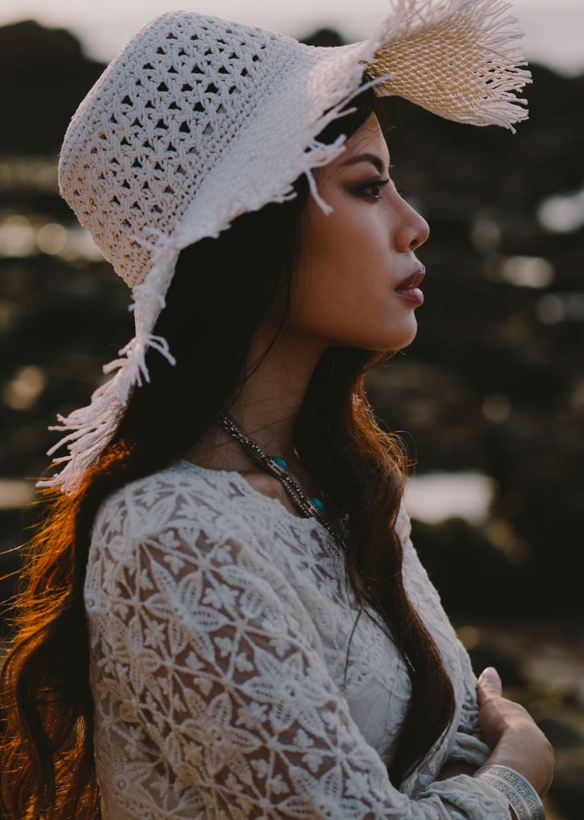 Woman with a sun hat and lace blouse.