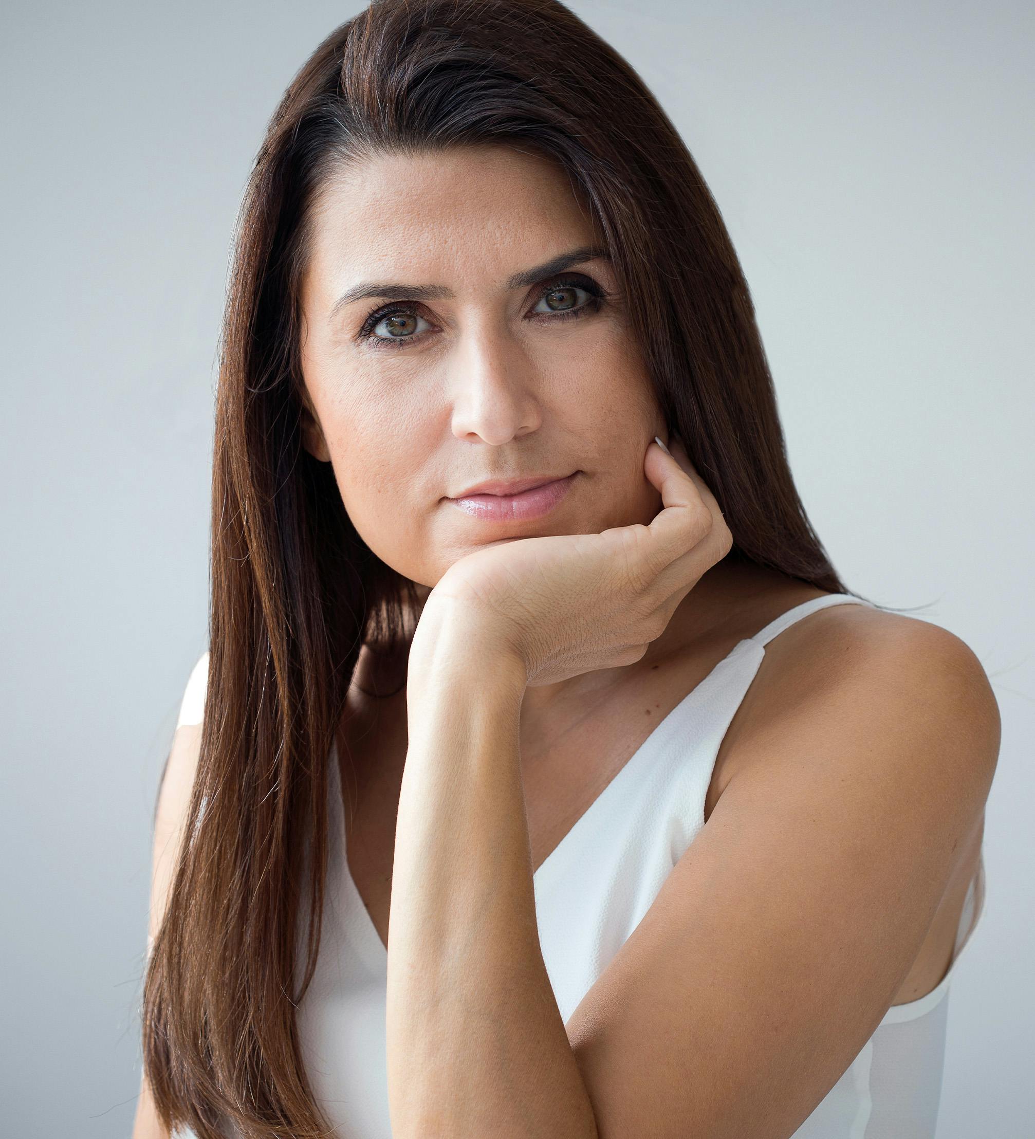 Brunette woman with her chin on her hand.