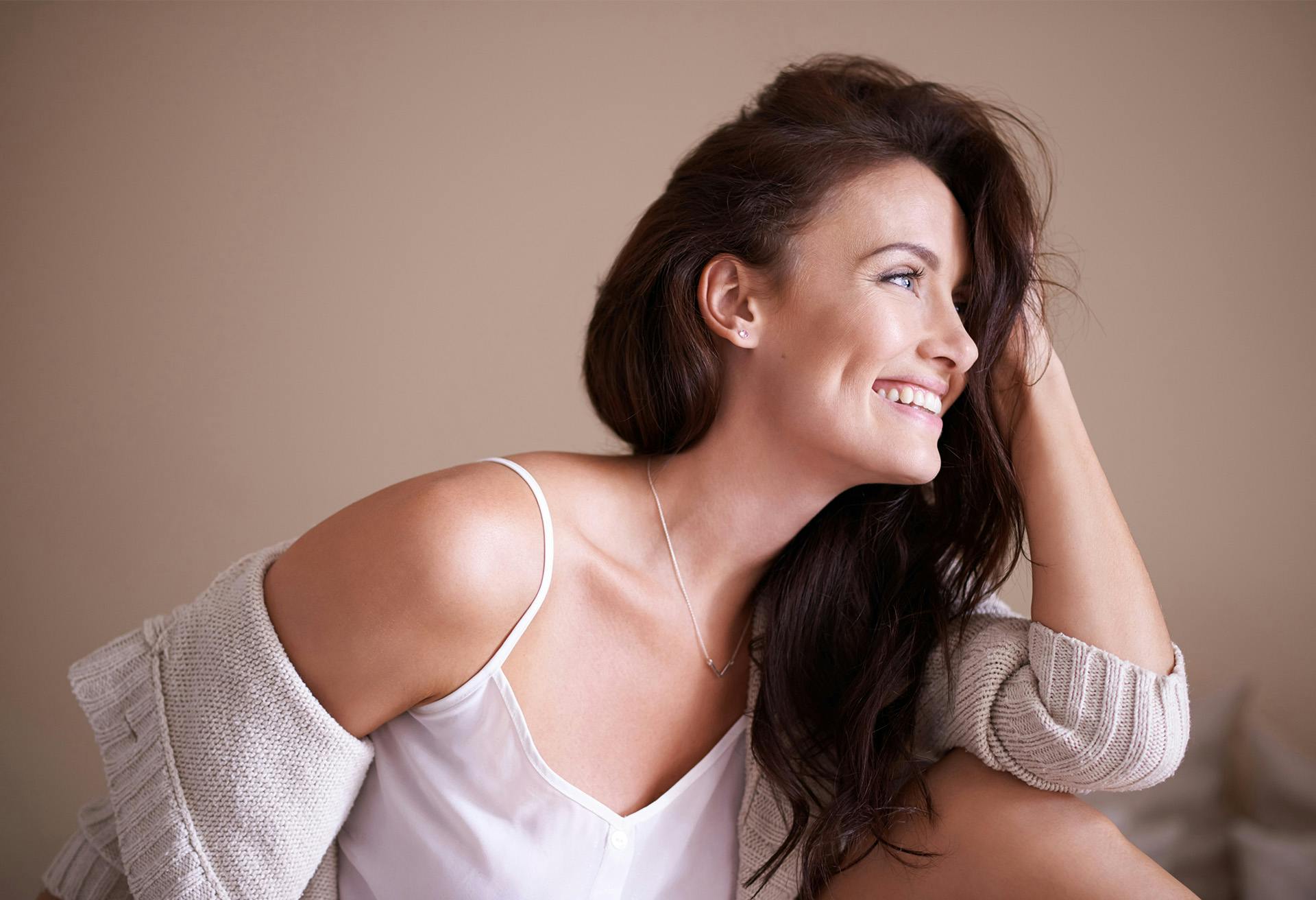 Woman holding her hair and smiling looking to the side.