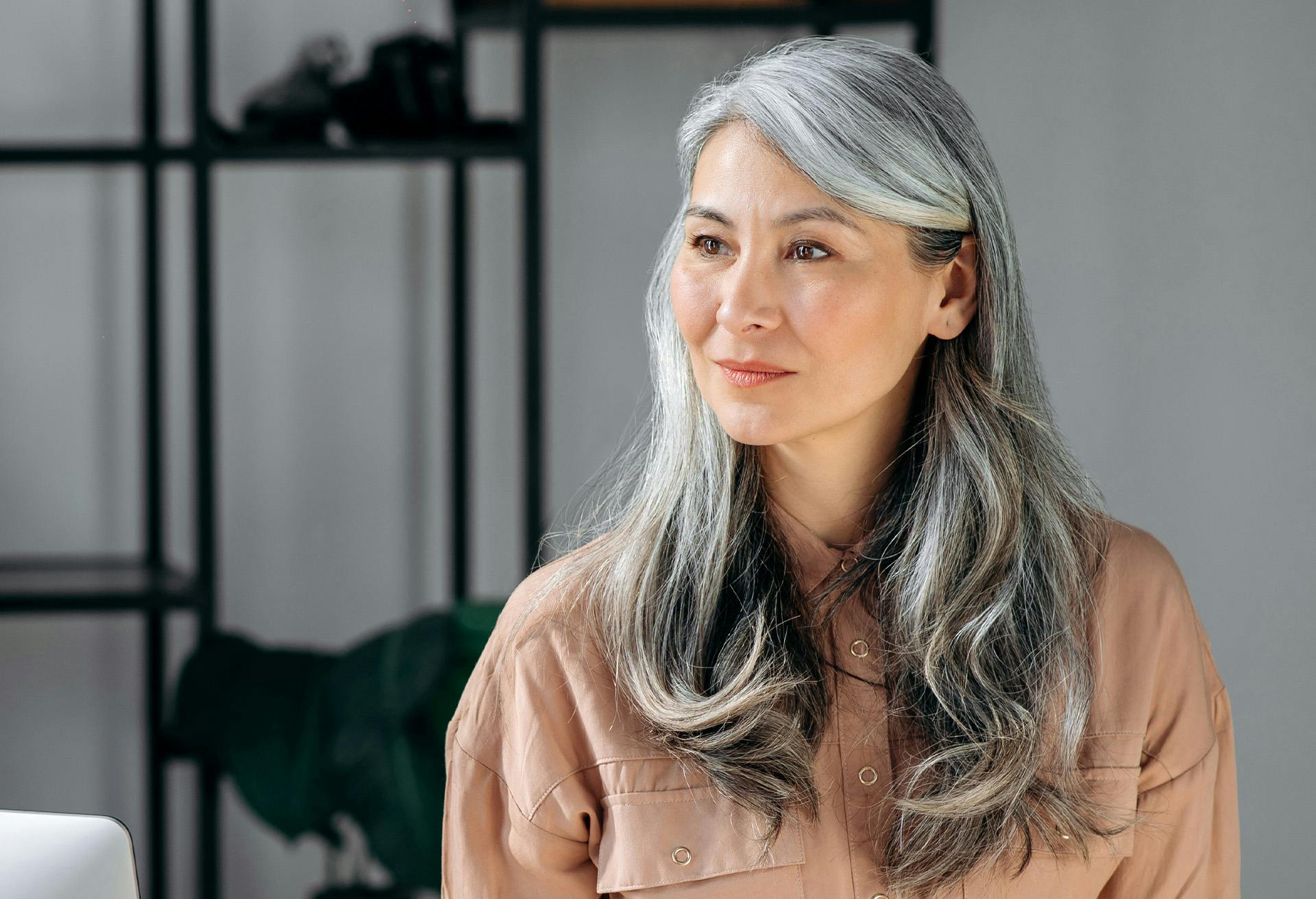Grey haired woman smiling and looking to the side.