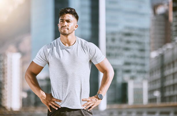 Man with hands on his hips and city in the background