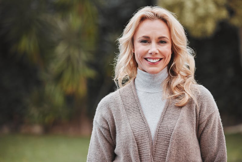 Older blonde woman in a sweater outside
