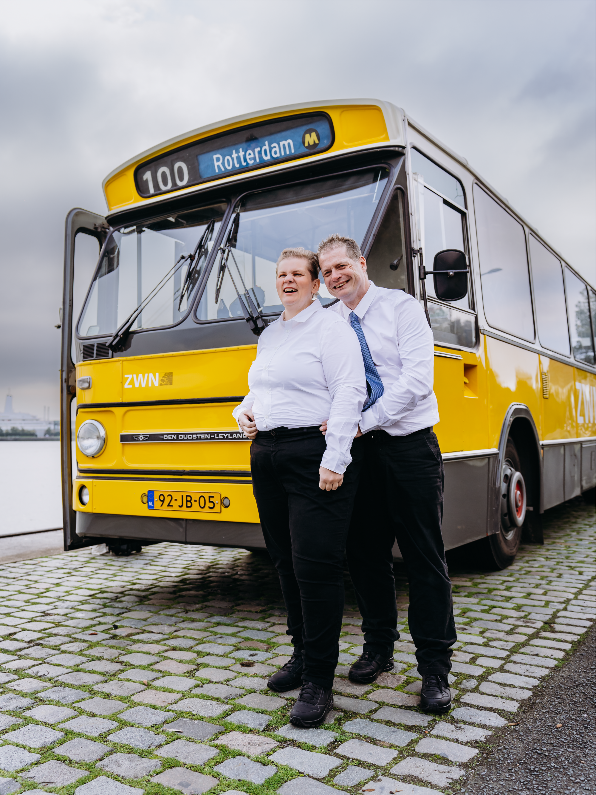 Buschauffeur couple voor een gele bus