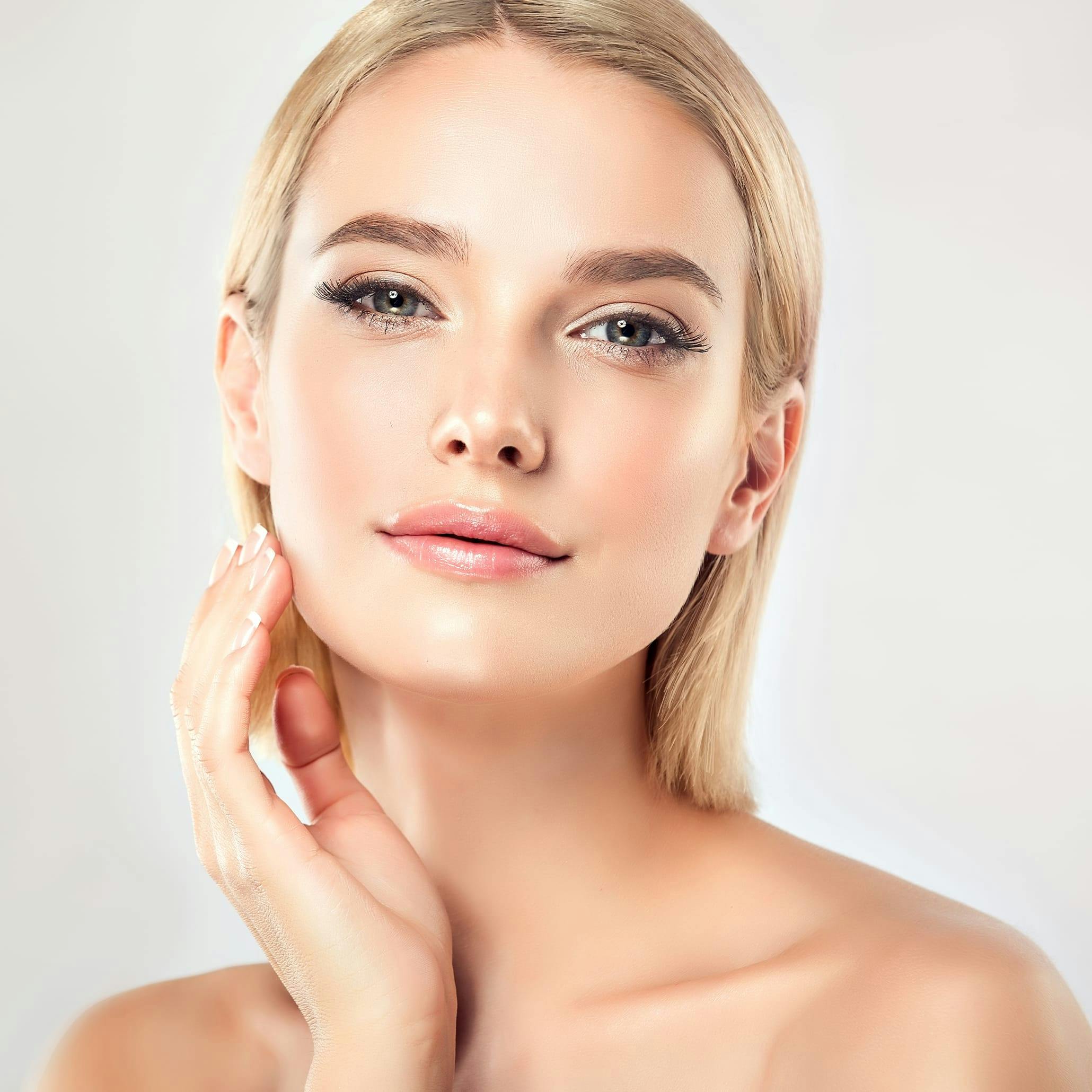Blonde woman with perfect skin, touching her lower face