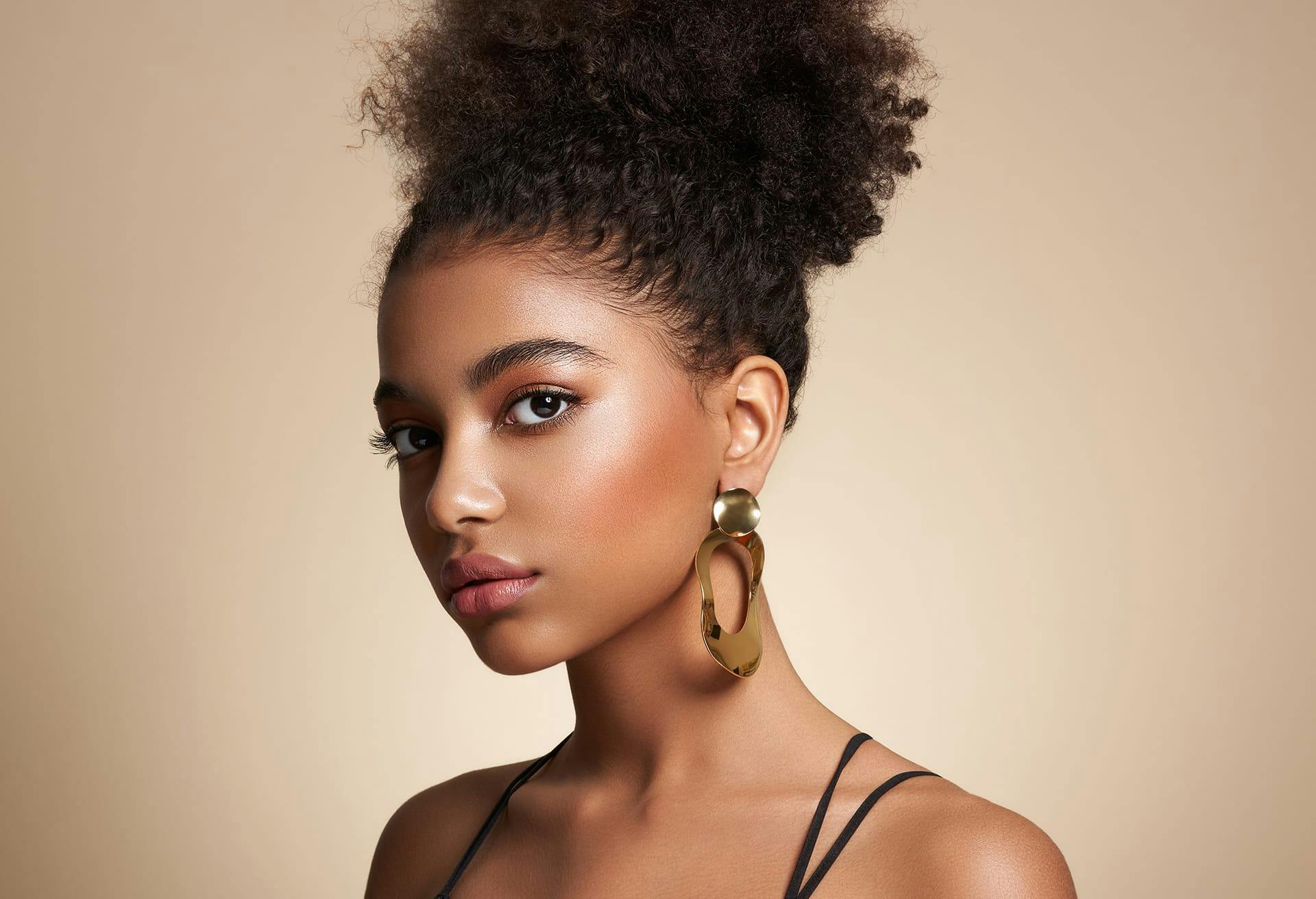 Beautiful woman wearing big gold earrings with her curly hair in an updo