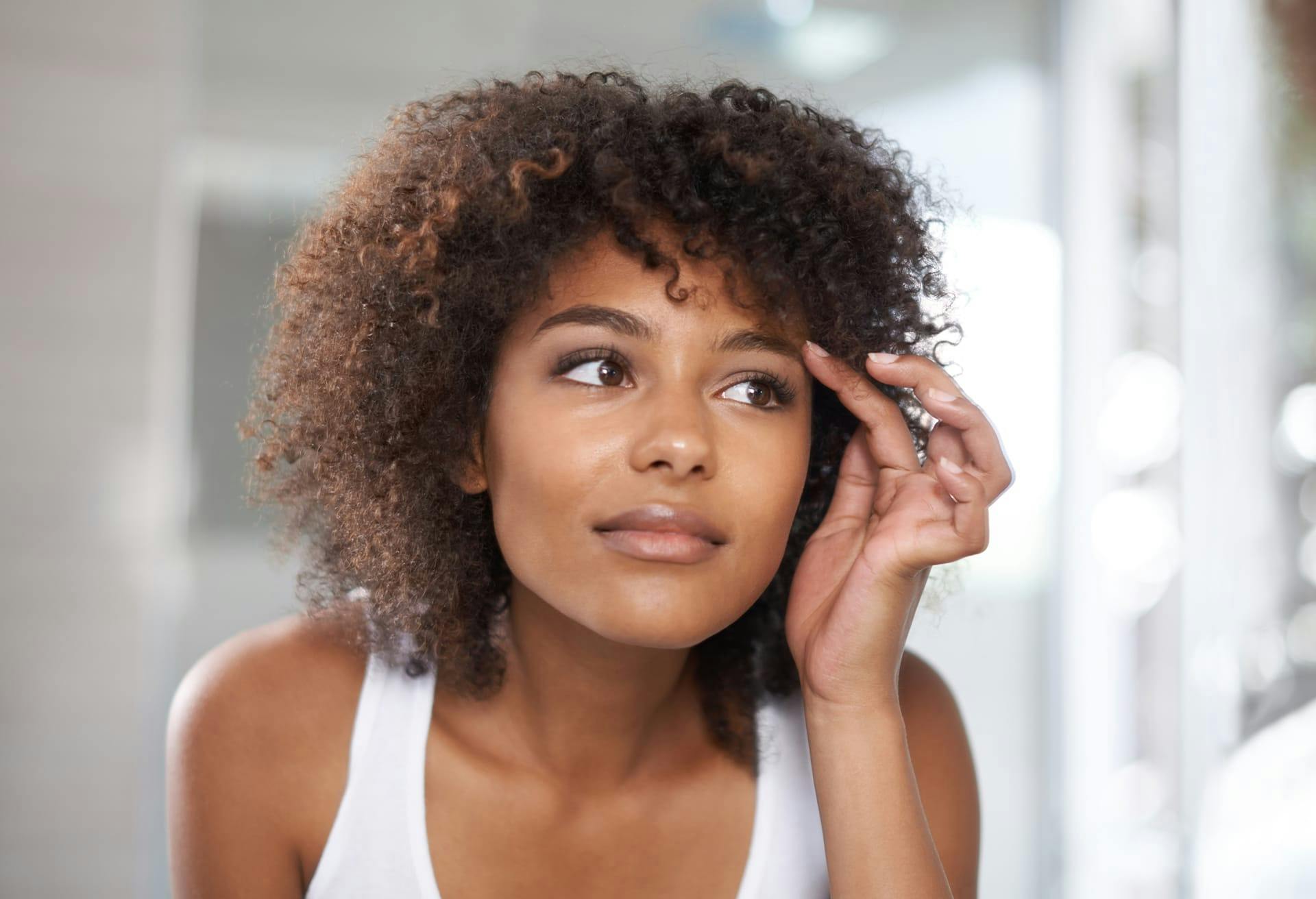 woman inspecting face in mirror