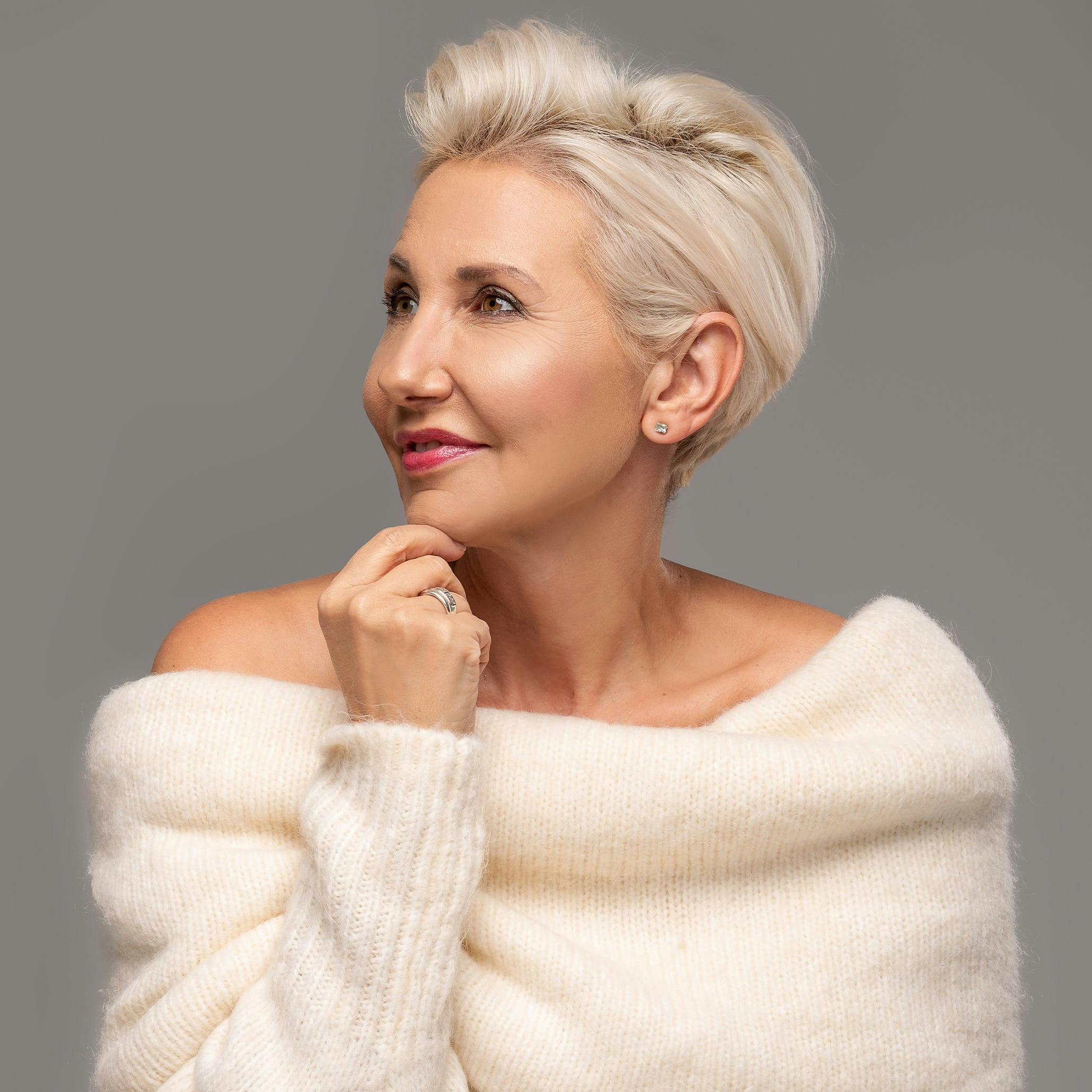 Glamorous woman with short grey/white hair and a big white sweater