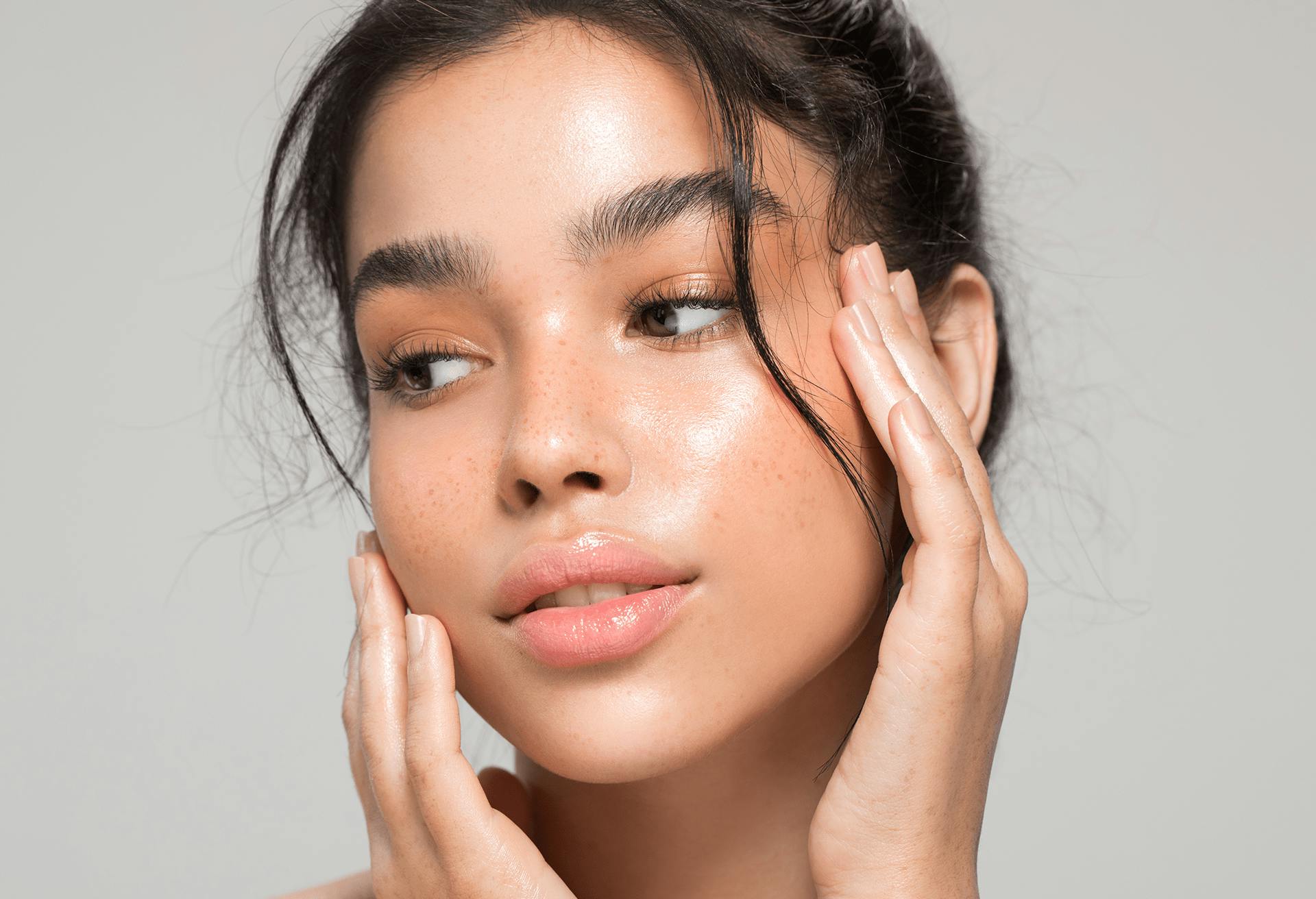 Beautiful girl with dewy skin touching her face