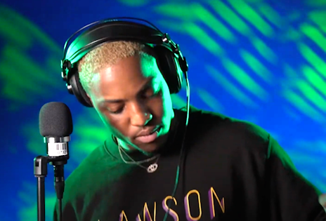 Muzikant hiphop Lawson staat in de Clickt studio bij een microfoon met een koptelefoon op.
