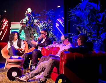 Beelden van PoV Live, Zyen en andere Hiphop studenten zitten op een bank op het podium en praten over de stelling of de mens muziek nodig heeft.